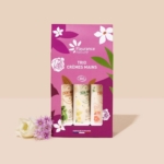 Coffret de crèmes pour les mains Fleurance Nature Trio Crèmes Mains avec un motif floral sur un emballage violet et rose, accompagné de petites fleurs violettes et blanches placées devant. Dakar