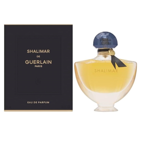 Un flacon d'Eau de Parfum Shalimar de Guerlain avec un liquide doré pâle, à côté de son emballage noir et or. Le flacon est muni d'un bouchon bleu et d'un petit nœud noir autour du col. Dakar