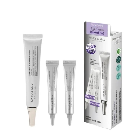 Trois tubes blancs de Mary & May Tranexamic Acid + Glutathione Eye Cream sont présentés à côté de leur boîte d'emballage, qui est blanche avec une étiquette violette et les détails du produit. Dakar