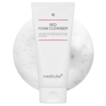 Un tube blanc étiqueté "Red Foam Cleanser" de Medicube est présenté devant un fond texturé et mousseux. Le tube présente un design minimaliste avec un texte rouge et gris. Dakar