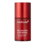 Une bouteille rouge de Medicube Red Succinic Acid Serum avec un texte blanc détaillant le nom du produit et les ingrédients clés, debout sur un fond blanc. Dakar