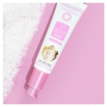 Un tube rose et blanc de 30 ml de Musc Intime Gel parfumant l'irrésistible au Musc Blanc se trouve à côté de cristaux blancs sur un fond rose, avec des étiquettes décoratives or et roses. Dakar