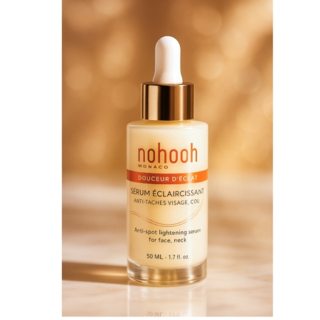 Un flacon de Nohooh Sérum Éclaircissant Anti Taches Visage Cou 50 ml avec un bouchon compte-gouttes doré, étiqueté pour le visage et le cou, se détache sur un fond chaud et flou. Dakar