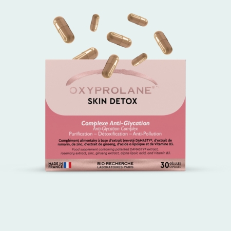 Une boîte de gélules Oxyprolane Skin Detox avec plusieurs gélules en vrac au-dessus d'elle. La boîte est rose et blanche, étiquetée pour l'anti-glycation, la purification, la désintoxication et l'anti-pollution, et contient 30 gélules. Dakar