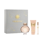 Un coffret cadeau contenant une boîte Rabanne grise et dorée, un flacon rond de parfum Olympea, un tube de lotion pour le corps et un vaporisateur de voyage fin, tous avec des motifs assortis or et rose blush. Dakar