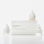 Trois flacons compte-gouttes du Coffret d'Ampoules pour Éclat et Anti Age à la Centella de Madagascar 3 pièces de Skin1004 sont présentés sur un fond blanc, dans un emballage minimaliste avec de subtiles étiquettes colorées pour un look moderne. Dakar