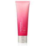 Un tube de mousse nettoyante Estée Lauder Nutritious 2-in-1 en dégradé rose et rouge se tient debout sur un fond blanc. L'emballage comporte un texte blanc et argenté et un bouchon argenté. Dakar