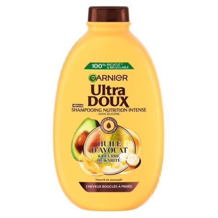 Une bouteille jaune de 600ml de Garnier Shampooing Nourrissant à l'Huile d'Avocat et Beurre de Karité Ultra Doux pour les cheveux frisés et crépus. L'étiquette française indique l'avocat et le karité, ainsi qu'un emballage 100% recyclé. Dakar