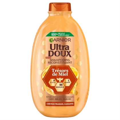 Un flacon de 600 ml de Garnier Ultra Doux Shampooing Reconstituant Trésors de Miel pour cheveux fragiles et abîmés, avec des motifs en nid d'abeille et des ingrédients d'acacia, de manuka et de lavande sur son étiquette orange. Dakar