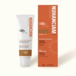 Un tube et une boîte de crème teintée de protection solaire NUHANCIAM Paris SPF 50+ pour les peaux foncées, avec un emballage orange et blanc avec des graphiques solaires et des détails sur le produit en français et en anglais. Dakar