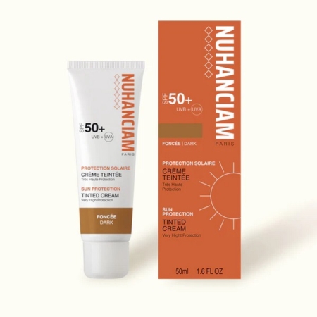 Un tube et une boîte de crème teintée de protection solaire NUHANCIAM Paris SPF 50+ pour les peaux foncées, avec un emballage orange et blanc avec des graphiques solaires et des détails sur le produit en français et en anglais. Dakar