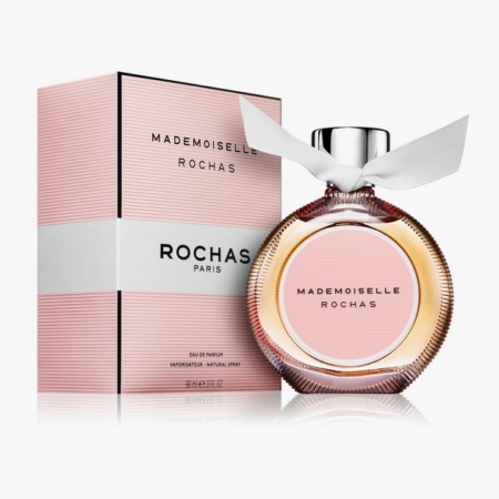 Un flacon de parfum Mademoiselle Rochas avec un ruban blanc sur le bouchon est placé à côté de son coffret rayé rose et blanc, tous deux portant le nom de la marque "Rochas Paris" sur la face avant. Dakar
