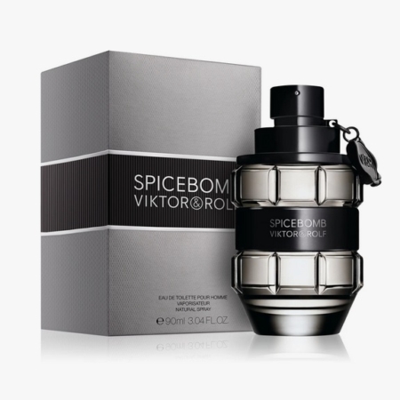 Un flacon de Viktor&Rolf Spicebomb Eau de Toilette est montré à côté de sa boîte grise assortie. Le flacon ressemble à une grenade, avec une bande noire et une marque au milieu. La boîte affiche le nom et les détails du produit. Dakar