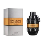 Un flacon de Viktor & Rolf Spicebomb Extreme Eau de Parfum se trouve à côté de son emballage argenté et doré. Le flacon noir en forme de grenade porte une étiquette dorée avec un texte noir. Dakar