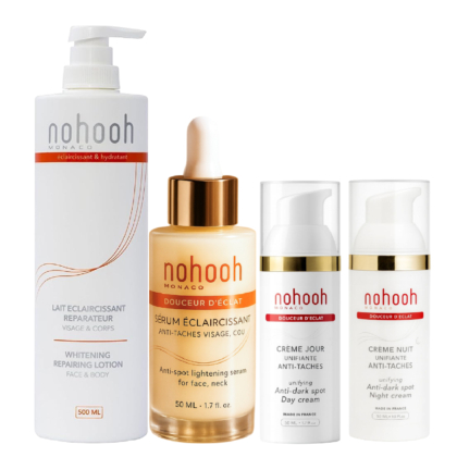 Quatre produits de soin de la marque Nohooh Monaco, dont une lotion réparatrice blanchissante, un sérum éclaircissant avec compte-gouttes, une crème de jour et une crème de nuit, le tout dans un emballage blanc et or aux accents orangés. Dakar
