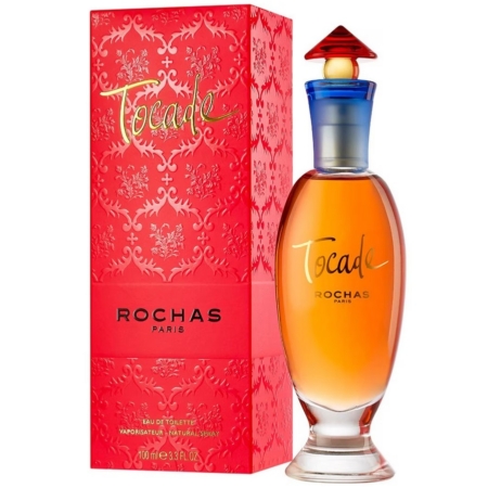 Un flacon de parfum Rochas Tocade avec un bouchon orange et bleu est posé à côté de sa boîte décorative rouge, tous deux affichant la marque et le nom du parfum en élégantes lettres dorées et blanches. Dakar