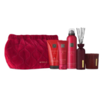 Une pochette rouge matelassée Rituals contenant quatre produits Rituals : une crème pour le corps, une mousse de douche, un tube, un diffuseur à anche et une bougie, tous dans un emballage rouge assorti, disposés en rang sur un fond blanc. Dakar