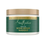 Une boîte de SheaMoisture Amla Oil Bond Repair Masque avec un couvercle doré et une étiquette verte, qui prétend réparer les liens endommagés des cheveux et réduire les cassures de 84%. Dakar