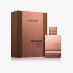 Un flacon de parfum de couleur cuivre étiqueté "Haramain Amber Oud Tobacco Edition" se trouve à côté d'une boîte rectangulaire assortie portant le même texte et la mention "Al Haramain Since 1970" imprimée dans la partie supérieure. Dakar
