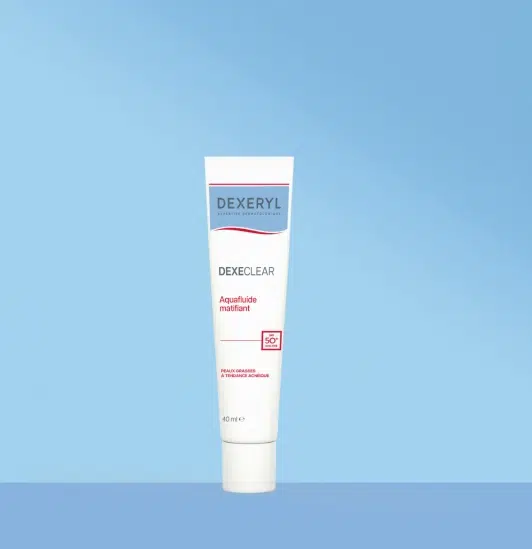 Un tube blanc de crème matifiante pour le visage Dexeryl Aquafluide avec SPF 50+ se tient debout sur un fond bleu. Dakar