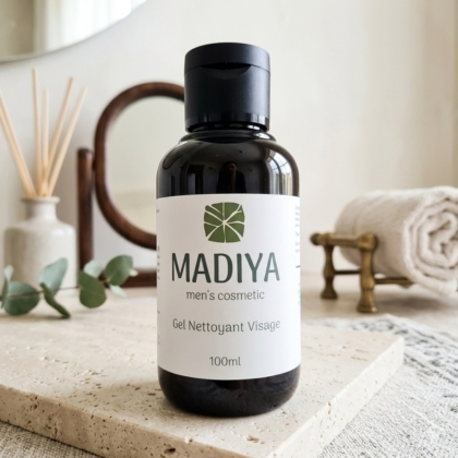 Un flacon de gel cosmétique nettoyant pour hommes MADIYA (100 ml) est posé sur un plateau en pierre dans une salle de bains minimaliste, avec une serviette enroulée, de la verdure et un décor en arrière-plan. Dakar