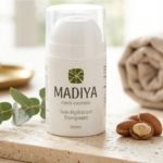 Un flacon de Madiya Men's Cosmetic Soin Hydratant Énergisant 100ml est posé sur une surface en pierre avec des noix d'argan et des feuilles vertes, soulignant les qualités naturelles et revitalisantes du produit. Dakar