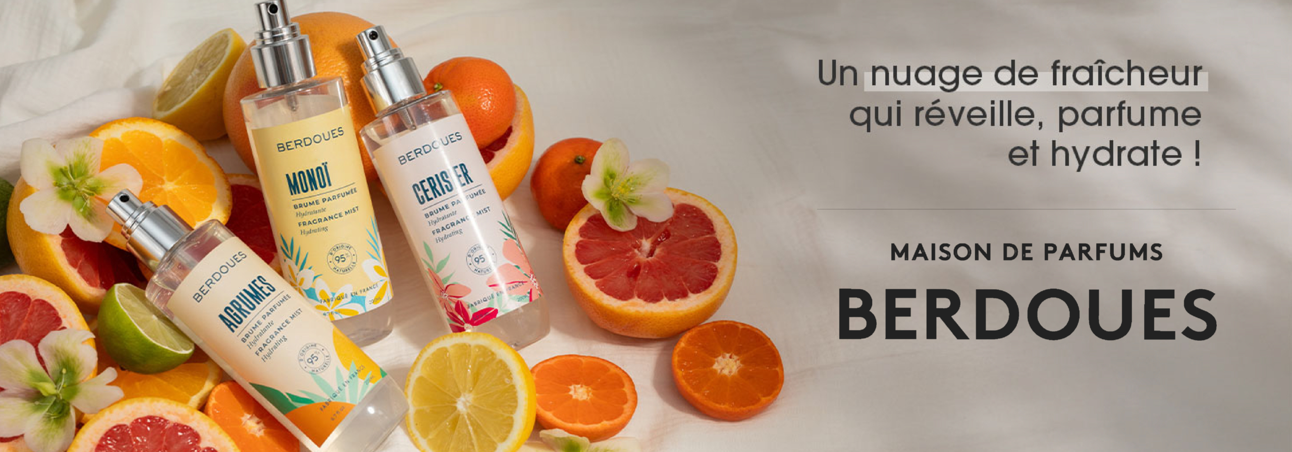 Quatre flacons de parfum Berdoues colorés sont présentés parmi des agrumes et des fleurs fraîches sur une surface claire. Un texte en français fait la promotion d'une brume rafraîchissante, parfumée et hydratante d'Univers Cosmetix. La mention "Maison de Parfums Berdoues" est mise en évidence. Dakar
