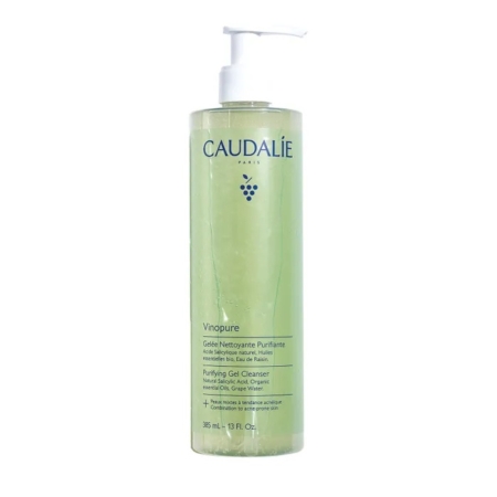 Un flacon transparent de Caudalie Vinopure Gelée Nettoyante Purifiante 385ml avec une pompe blanche, rempli de gel vert clair. L'étiquette bilingue affiche les détails du produit. Associez-le à Caudalie Vinopure Stop Boutons Salicylique 15ml pour un soin ciblé. Dakar