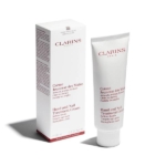 Un tube et une boîte de crème de traitement des mains et des ongles Clarins Paris sont présentés debout. Les deux sont blancs avec un texte rouge décrivant le produit en français et en anglais. La boîte est placée à gauche du tube. Dakar