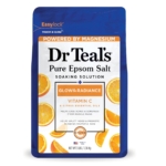 Un sachet bleu et blanc de Dr Teal's Pure Epsom Salt Soaking Solution, étiqueté "Glow & Radiance" avec de la vitamine C et des huiles essentielles d'agrumes. L'emballage présente des tranches d'orange et souligne la teneur en magnésium. Dakar