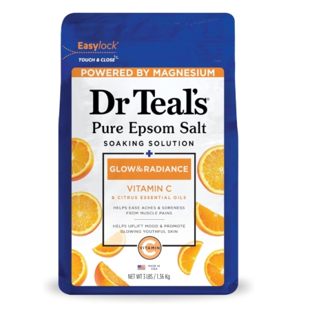 Un sachet bleu et blanc de Dr Teal's Pure Epsom Salt Soaking Solution, étiqueté "Glow & Radiance" avec de la vitamine C et des huiles essentielles d'agrumes. L'emballage présente des tranches d'orange et souligne la teneur en magnésium. Dakar