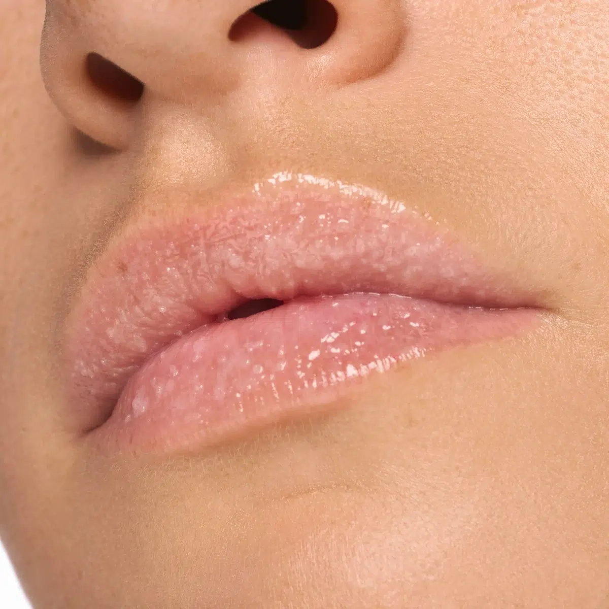 Gros plan sur les lèvres d'une personne au ton rose naturel, portant un baume à lèvres brillant et transparent. La peau est lisse et les lèvres semblent hydratées et saines. Dakar