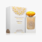 Un flacon de parfum Musk Collection Piña Colada avec un bouchon jaune est présenté à côté de sa boîte décorative blanche et dorée. Tous deux sont ornés de motifs dorés et de textes en anglais et en arabe. Dakar