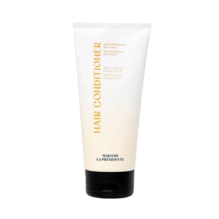 Un tube blanc d'après-shampoing Madame La Présidente avec un bouchon noir et un texte doré, debout sur un fond uni. Dakar