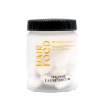 Un pot en plastique blanc avec un couvercle noir étiqueté "HAIR FOOD" et "RESOLUTION N°1" en texte jaune et noir, contenant des capsules blanches. La marque "MADAME LA PRÉSIDENTE" est imprimée en bas. Dakar