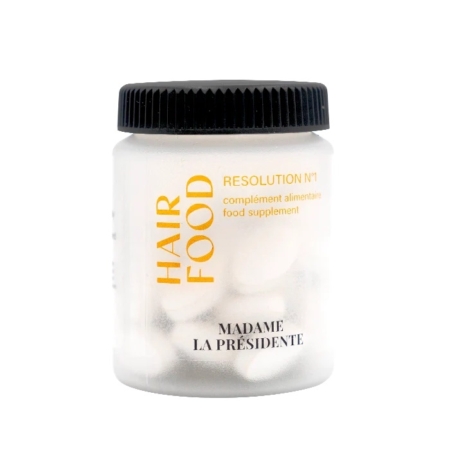 Un pot en plastique blanc avec un couvercle noir étiqueté "HAIR FOOD" et "RESOLUTION N°1" en texte jaune et noir, contenant des capsules blanches. La marque "MADAME LA PRÉSIDENTE" est imprimée en bas. Dakar