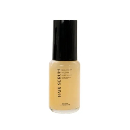 Une bouteille transparente avec un bouchon noir contenant un liquide beige clair étiqueté "Hair Serum". L'étiquette comporte également un texte plus petit et le nom de la marque "Mavue La Prominente". Dakar