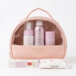 Une trousse de toilette rose à l'avant transparent présente quatre produits de soins personnels rose pastel et un paquet de lingettes, tous étiquetés "Musc Intime". La trousse est munie d'une poignée et d'une fermeture éclair dorée. Dakar