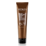 Un tube brun étiqueté "Redken All Soft Mega Curls Hydramelt Treatment" se tient debout. La face avant présente les détails du produit, y compris sa taille : 150 ml (5.1 fl oz), et mentionne un Complexe Nourrissant de 7%. Dakar