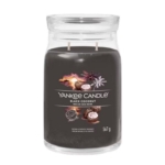 Une grande bougie en verre étiquetée "Yankee Candle Black Coconut" avec des images de noix de coco, de palmiers et d'un coucher de soleil sur la face avant. La cire de la bougie est brun foncé ou noire et comporte deux mèches. Le pot contient 567 grammes. Dakar