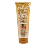Un tube doré de Mielle Organics Shampooing Apaisant A L'Avoine Et Au Miel 237ml pour cuir chevelu sensible, avec des graphiques d'avoine et de miel, le logo de soutien de Susan G. Komen, inspiré de leur shampooing à la grenade et au miel. Dakar