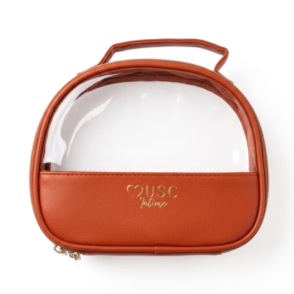 La Trousse Musc Intime (Copie) est une petite pochette cosmétique ovale en cuir marron avec une poignée, une partie supérieure en plastique transparent et une élégante marque dorée "USC Intime" sur le devant. Dakar