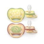 Deux sucettes pour bébé avec tétines en silicone ; l'une a des tons verts et jaunes avec un motif de feuilles, l'autre a des tons roses et jaunes avec un motif de plantes. Les deux tétines sont représentées de face et de côté. Dakar