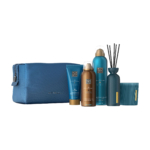 Une trousse de toilette bleue est présentée avec cinq produits de la marque Rituals : un tube, un bidon, un flacon, un diffuseur avec des roseaux et une bougie, le tout dans un emballage bleu et bronze assorti sur fond blanc. Dakar