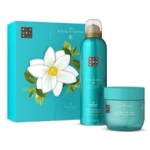 Un coffret cadeau Rituals turquoise avec un motif floral sur la boîte, un flacon de mousse de douche et un pot de masque corporel de la collection "The Ritual of Karma" présentés devant. Dakar