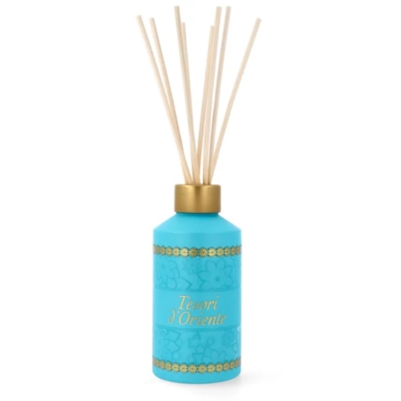 Un flacon diffuseur de parfum Tesori d'Oriente bleu avec des accents dorés et plusieurs roseaux en bois insérés dans la partie supérieure, debout sur un fond blanc. Dakar