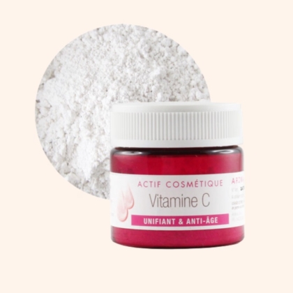 Un petit pot rouge portant l'étiquette « Aroma Zone Actif Melano'Regul Anti-Taches Unifiant 10 ml (Copie) » trône devant un cercle blanc poudreux, évoquant la puissance concentrée nécessaire à un teint uniforme et éclatant. Dakar