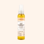 Un flacon vaporisateur transparent contenant l'huile démaquillante et nourrissante « Prune et Avoine » d'Aroma Zone (100 ml), présenté sur un fond beige clair uni. Dakar