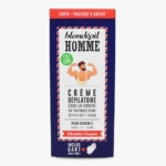 Boîte bleue et rouge de Blondépil Homme, crème dépilatoire de douche pour peaux sensibles, illustrée d'un homme barbu et musclé en train de faire des flexions, avec des informations sur le produit en français et en anglais sur la face avant. Dakar