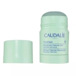 Un stick vert clair de déodorant naturel Caudalie Vinofresh 24 heures, dont le bouchon a été retiré et posé à côté. L'étiquette du produit est visible sur le tube. Dakar